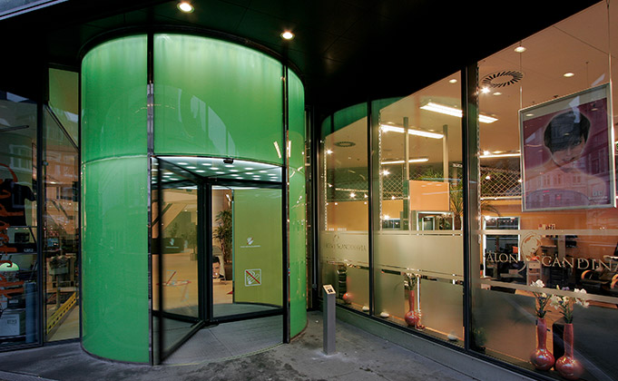 Modern building featuring an automatic revolving door within a green illuminated entrance