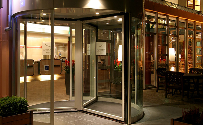 modern entrance system featuring a revolving door with automatic access control