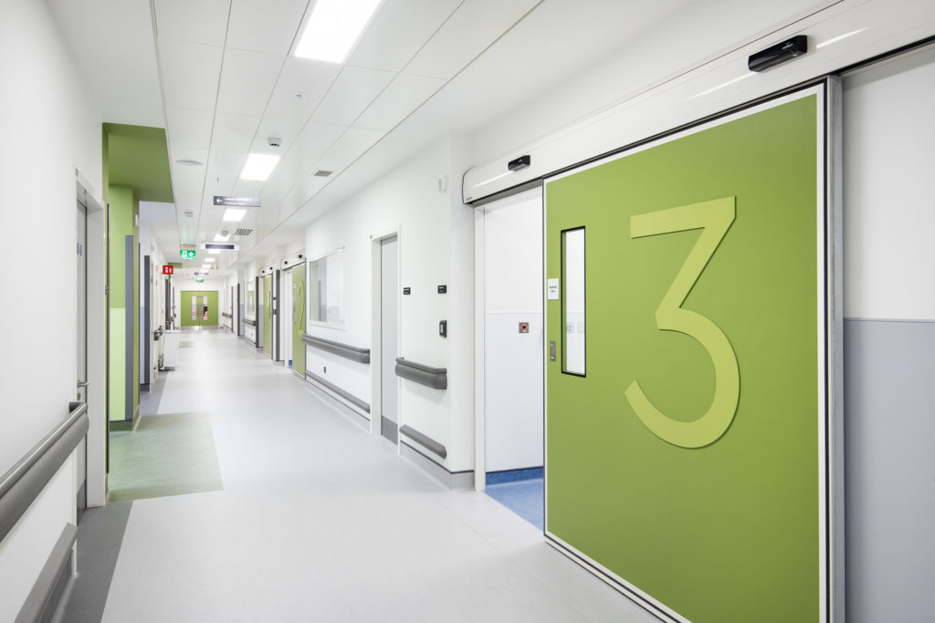 A hospital corridor with a green clean room doors for room number 3
