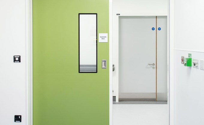 Cleanroom doors with integrated vision panel in green and a grey hygiene door in the background