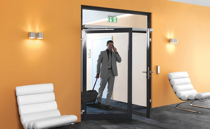 A man on his phone entering building through an automatic swing door