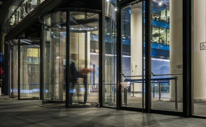 Entrance door systems from modern office building featuring revolving door to control the passage of movement