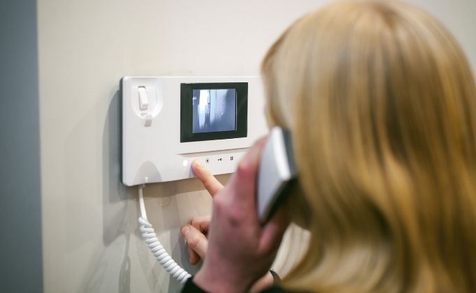 Woman uses audio video intercom system to screen guests visiting