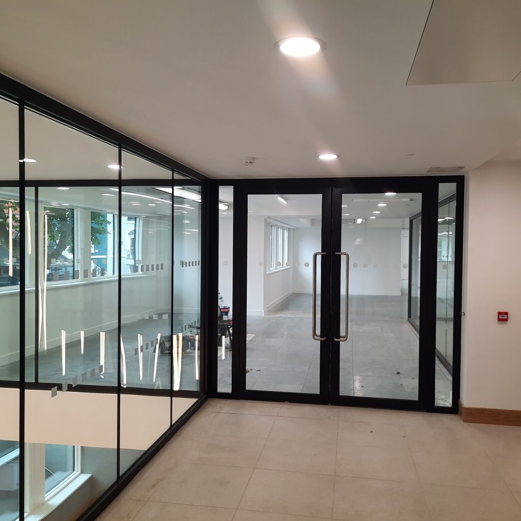 double fire-rated glazed steel doorset and adjacent large glazed wall in modern commercial office