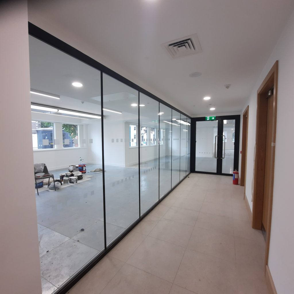 office corridor with slim framed glazed screen wall and glazed entrance door