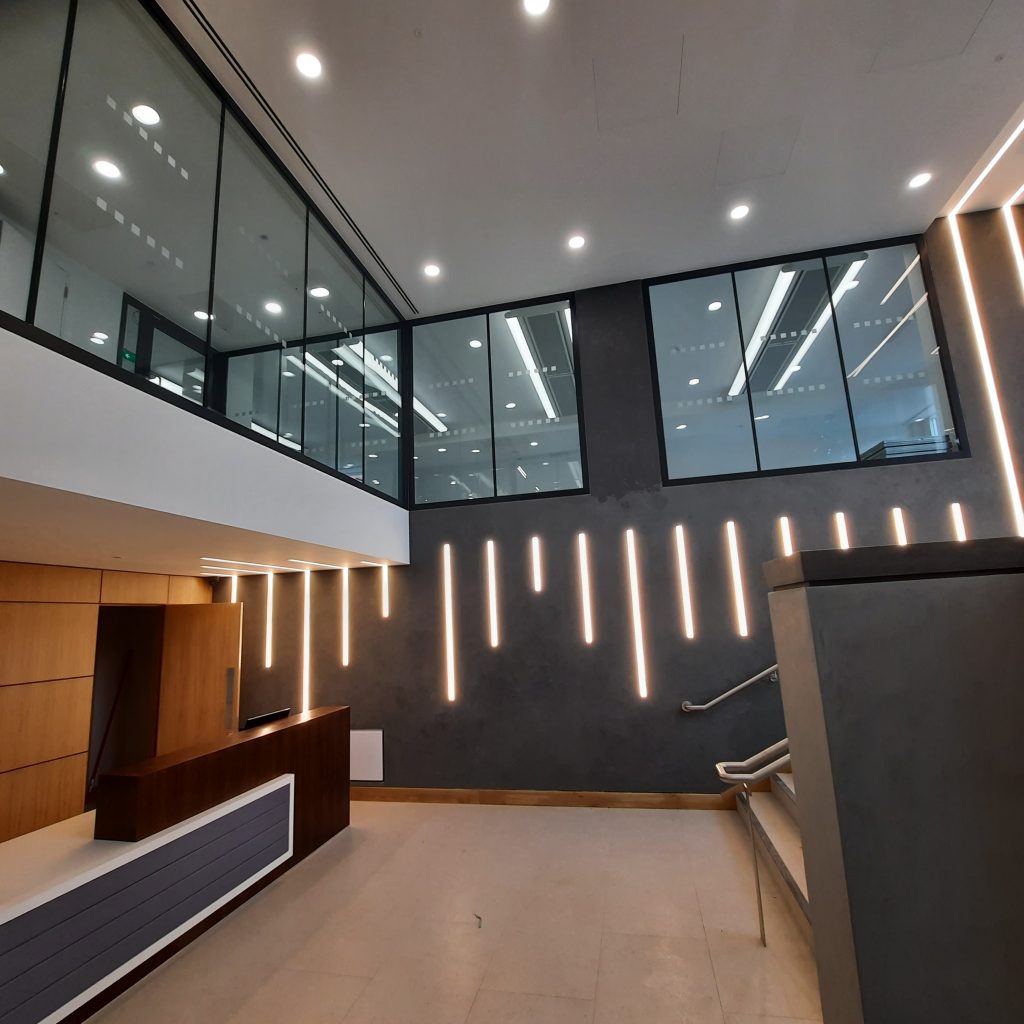 modern office lobby with two-storey high ceiling and upper glass sections overlooking main reception area