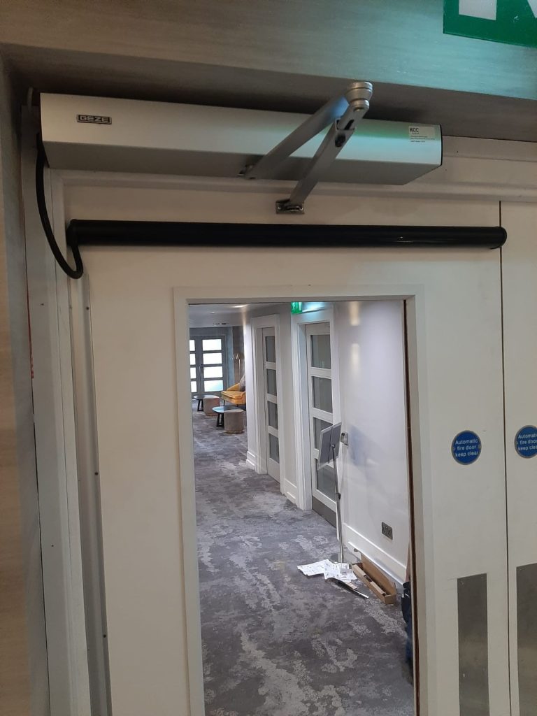 close up of automatic operator on timber doorset on hotel corridor