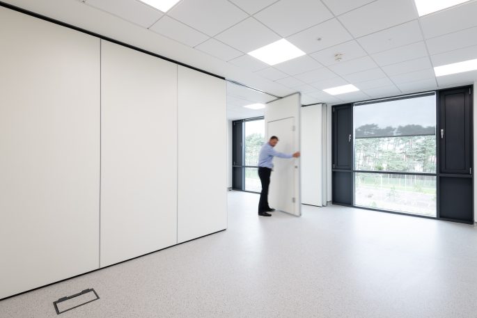 Solid walls and partitions - Man opening up the moveable solid partition wall to open up the office space fully.