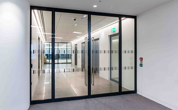Double fire rated glass doorset with fixed side screens in lift lobby