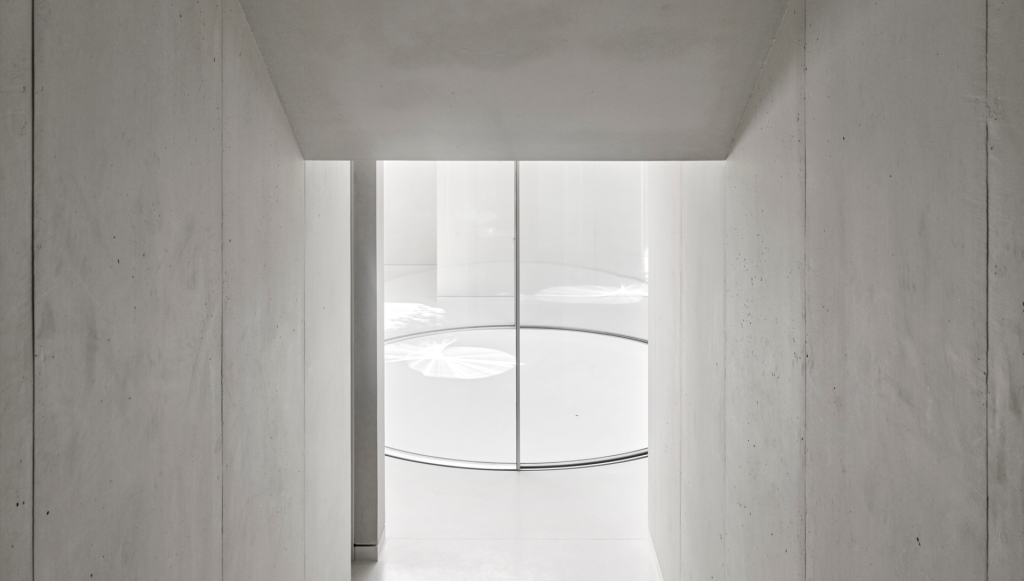 Wide angle view of curved glass doors in modern concrete finish room