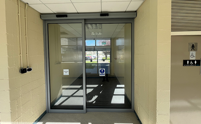 Looking at an internal automatic sliding door inside a building corridor, likely leading into a lobby area with another automatic sliding door leading outside.